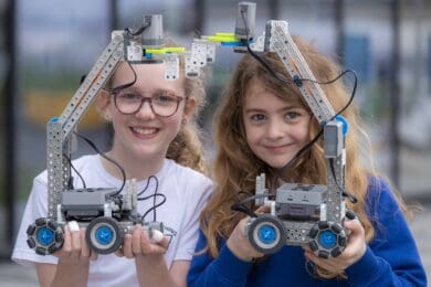 Two primary schoolchildren holding up the robots they have built