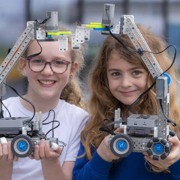 Two primary schoolchildren holding up the robots they have built