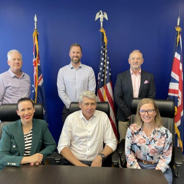 The executive team of H&B Defence in front of the flags of Australia, USA and UK