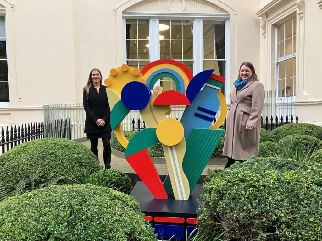 Louise Atkinson and Alice Kan stand behind a colourful sculpture outside the Royal Academy of Engineering